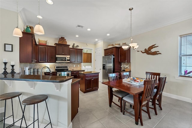 kitchen featuring kitchen peninsula, pendant lighting, stainless steel appliances, and a breakfast bar area