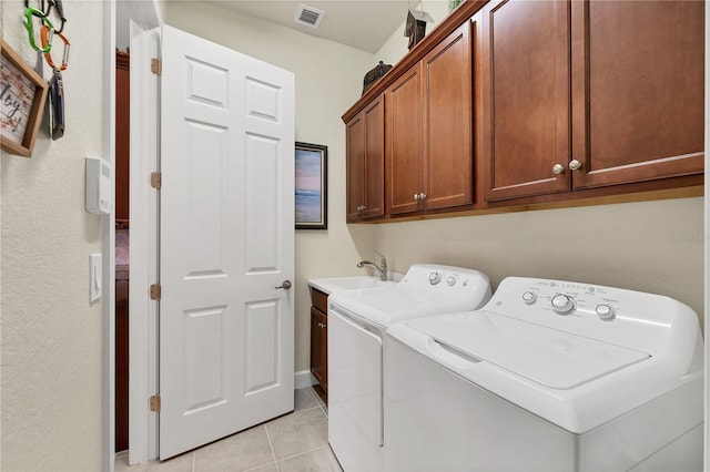 laundry room with washing machine and clothes dryer, sink, light tile patterned floors, and cabinets