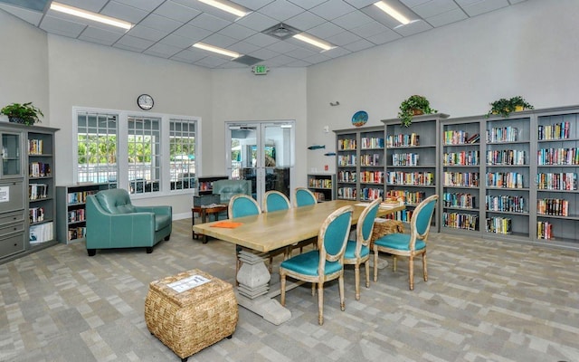 carpeted home office with a high ceiling and a drop ceiling