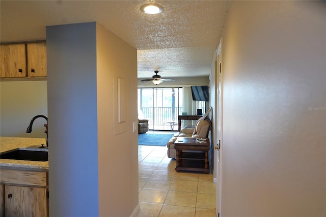 hall with light tile patterned floors, a textured ceiling, and sink