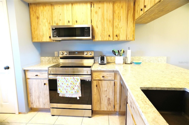 kitchen with sink, light tile patterned floors, and stainless steel appliances