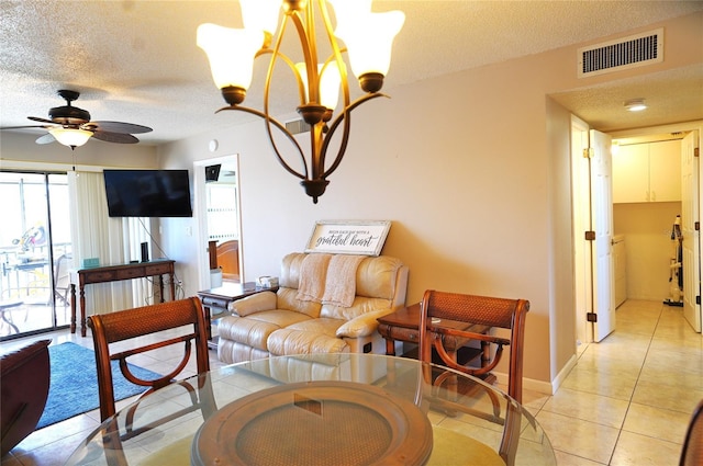 tiled living room with ceiling fan with notable chandelier and a textured ceiling