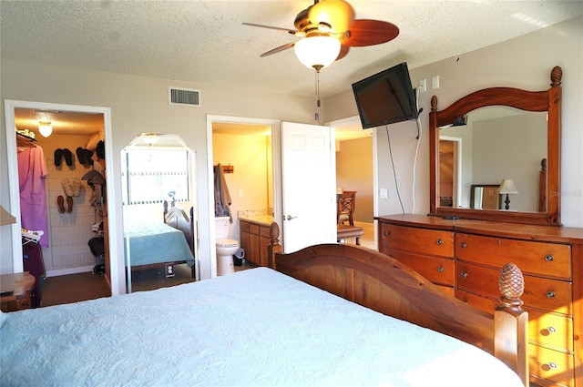 bedroom featuring a textured ceiling, connected bathroom, a closet, and ceiling fan