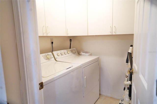 laundry area featuring washer and dryer, cabinets, and light tile patterned flooring