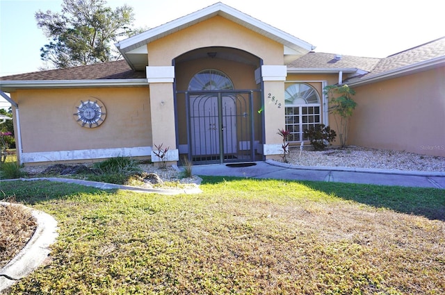 view of exterior entry with a lawn