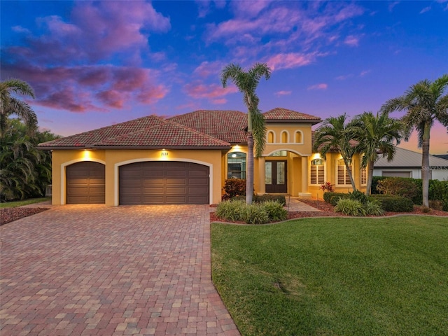 mediterranean / spanish-style home with a lawn, french doors, and a garage