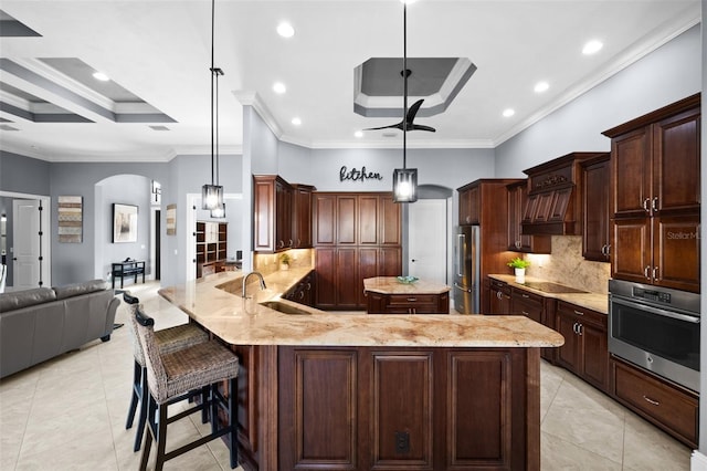 kitchen with a large island with sink, pendant lighting, stainless steel appliances, and sink