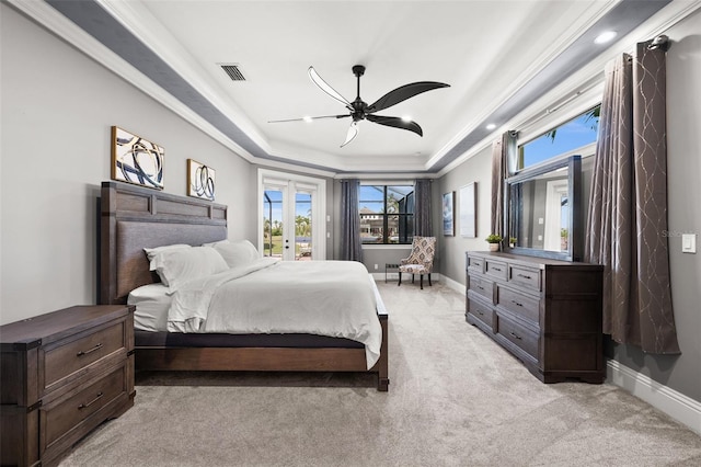 bedroom with a tray ceiling, ceiling fan, crown molding, and light colored carpet