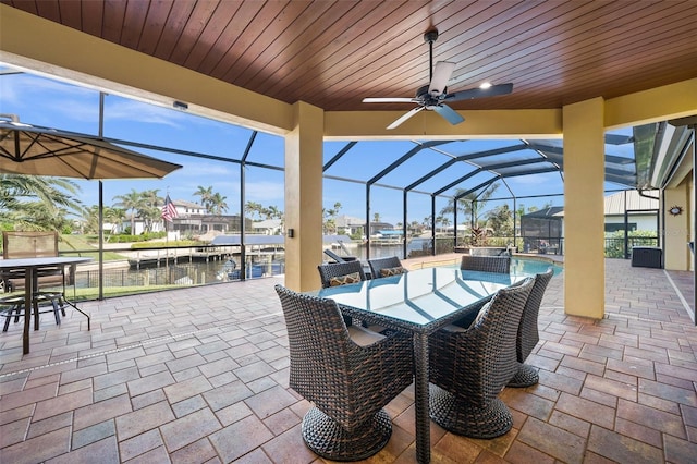 view of patio / terrace with ceiling fan, a water view, and glass enclosure