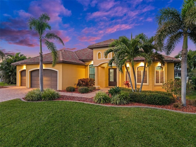 mediterranean / spanish-style home with a yard and a garage