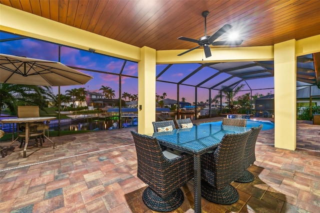 patio terrace at dusk featuring a lanai and ceiling fan