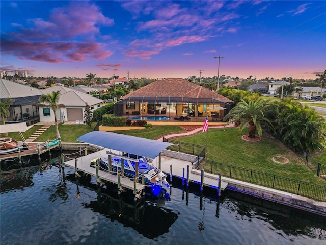 back house at dusk with a water view and a lawn