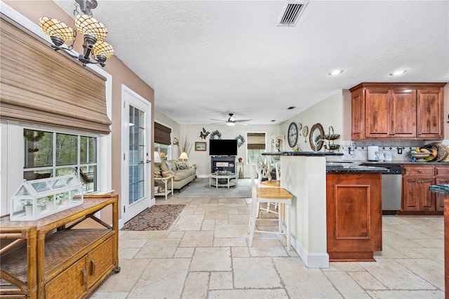 kitchen featuring a wealth of natural light, stainless steel dishwasher, a kitchen breakfast bar, and ceiling fan