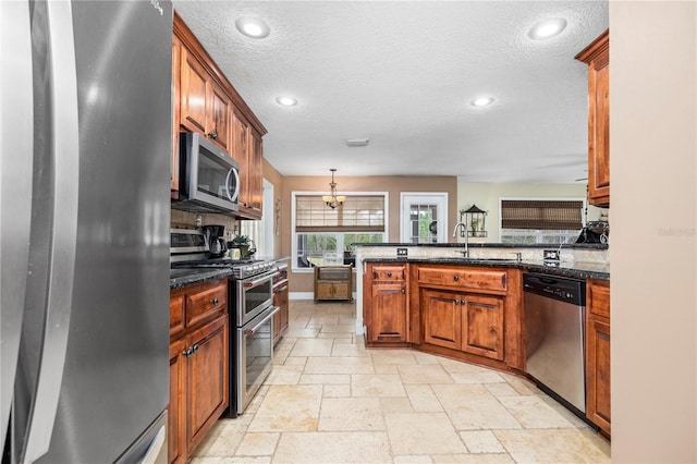 kitchen featuring decorative light fixtures, sink, dark stone countertops, stainless steel appliances, and an inviting chandelier