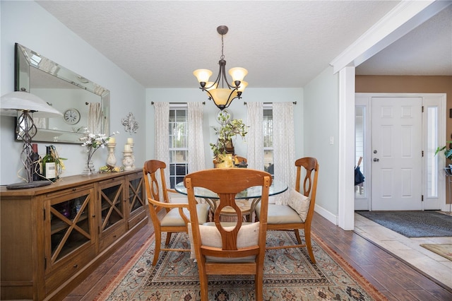 dining space with dark hardwood / wood-style flooring, a notable chandelier, and a textured ceiling