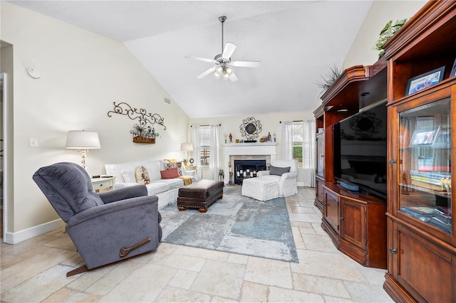 living room with ceiling fan, a tiled fireplace, and vaulted ceiling