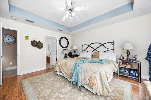 bedroom featuring hardwood / wood-style flooring, a raised ceiling, and ceiling fan