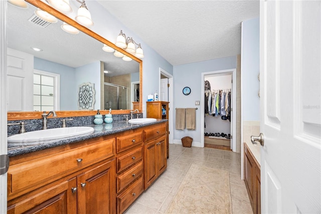 bathroom with tile patterned floors, vanity, an enclosed shower, and a textured ceiling