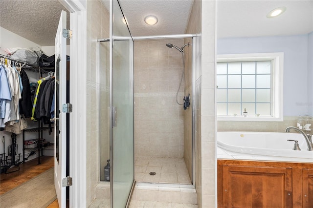 bathroom featuring wood-type flooring, shower with separate bathtub, and a textured ceiling