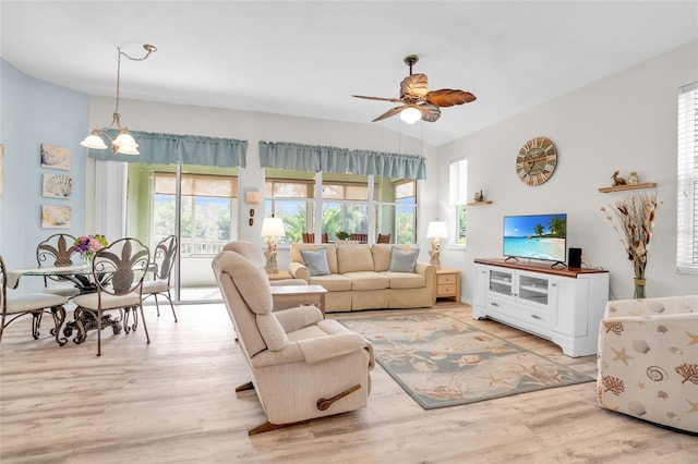 living room with vaulted ceiling, light hardwood / wood-style flooring, a healthy amount of sunlight, and ceiling fan with notable chandelier