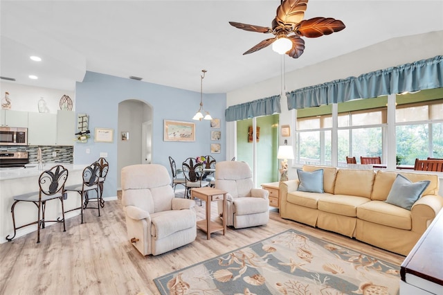 living room featuring vaulted ceiling, light hardwood / wood-style flooring, and ceiling fan