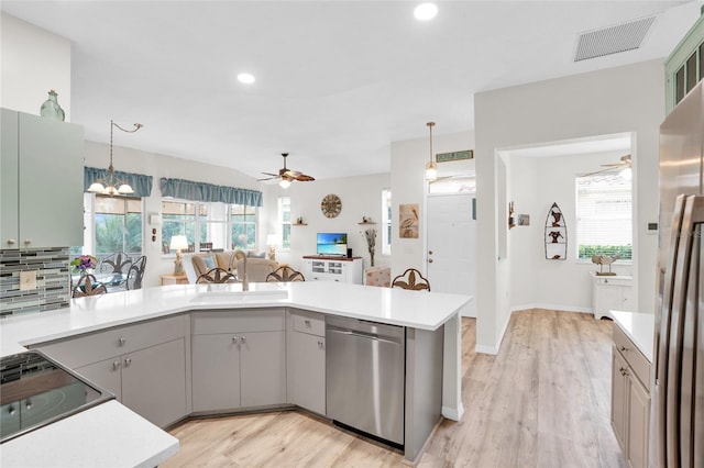 kitchen with pendant lighting, sink, appliances with stainless steel finishes, and light hardwood / wood-style flooring