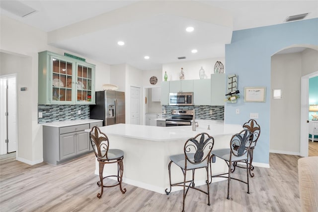 kitchen with kitchen peninsula, light hardwood / wood-style flooring, appliances with stainless steel finishes, and tasteful backsplash