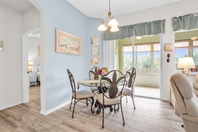 dining room with light wood-type flooring and an inviting chandelier