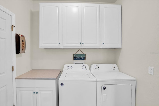 clothes washing area featuring cabinets and separate washer and dryer