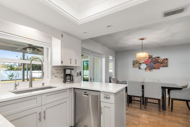 kitchen featuring stainless steel dishwasher, hanging light fixtures, and white cabinetry