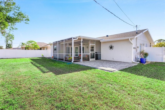 rear view of property featuring a patio, a lawn, and a sunroom