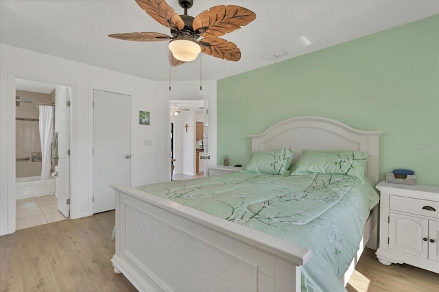 bedroom featuring ceiling fan, light hardwood / wood-style flooring, a textured ceiling, and ensuite bathroom