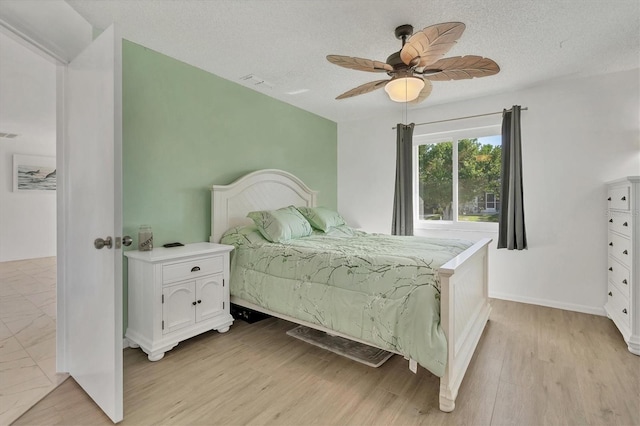 bedroom with light hardwood / wood-style flooring, ceiling fan, and a textured ceiling