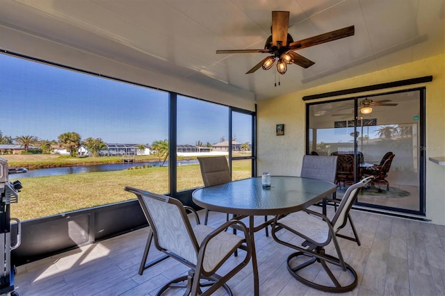 sunroom with a water view and ceiling fan