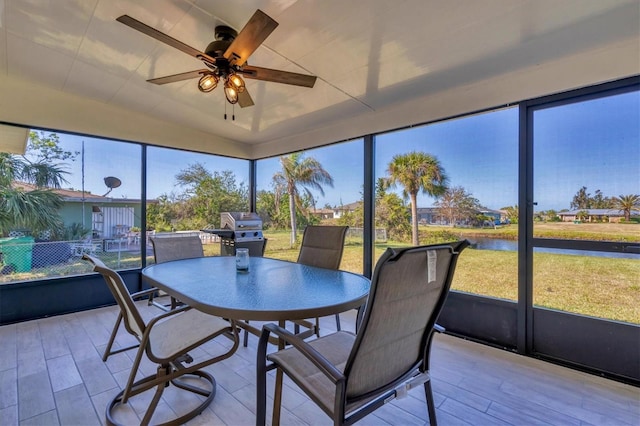 sunroom featuring ceiling fan and a water view