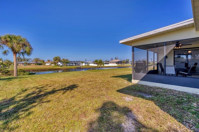 view of yard with ceiling fan, a water view, and a sunroom