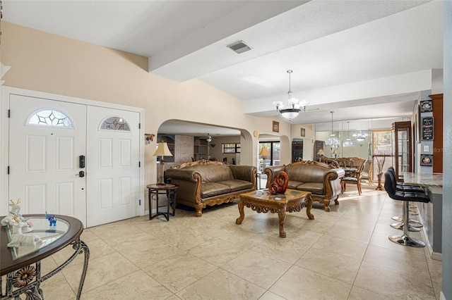 tiled living room featuring ceiling fan with notable chandelier and lofted ceiling