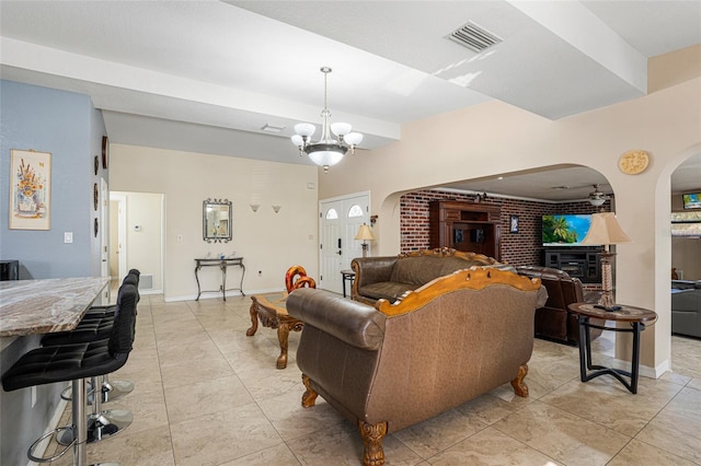 living room featuring a chandelier and brick wall