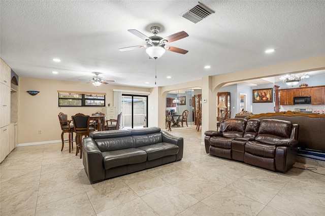 living room featuring ceiling fan and a textured ceiling