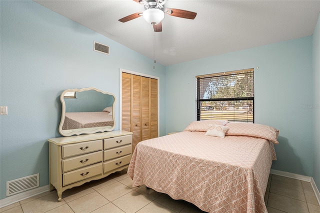 bedroom with ceiling fan, vaulted ceiling, light tile patterned floors, and a closet