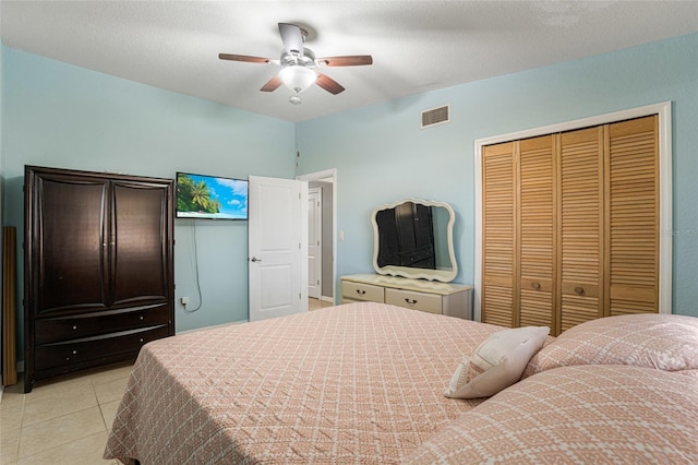 tiled bedroom with ceiling fan, a closet, and a textured ceiling