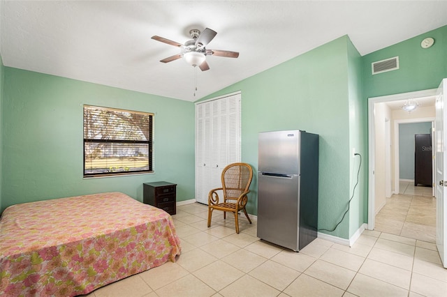 bedroom featuring stainless steel fridge, vaulted ceiling, ceiling fan, a closet, and light tile patterned flooring