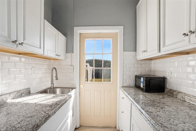 kitchen featuring white cabinets, light stone countertops, and sink