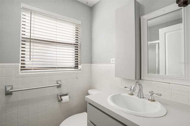 bathroom featuring vanity, tile walls, and toilet