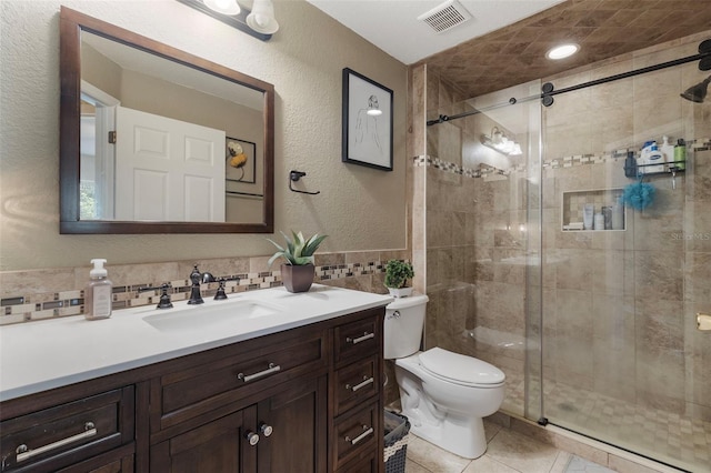 bathroom with tile walls, toilet, backsplash, a shower with door, and vanity