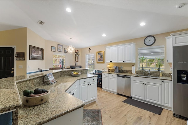 kitchen featuring appliances with stainless steel finishes, hanging light fixtures, white cabinets, light hardwood / wood-style flooring, and lofted ceiling