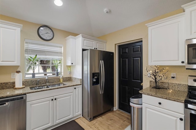 kitchen featuring stainless steel appliances, light wood-type flooring, dark stone counters, white cabinets, and sink