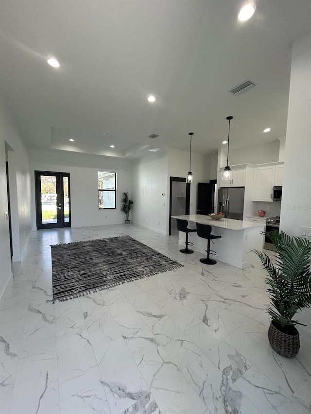 kitchen featuring appliances with stainless steel finishes, a breakfast bar, a kitchen island, decorative light fixtures, and white cabinetry