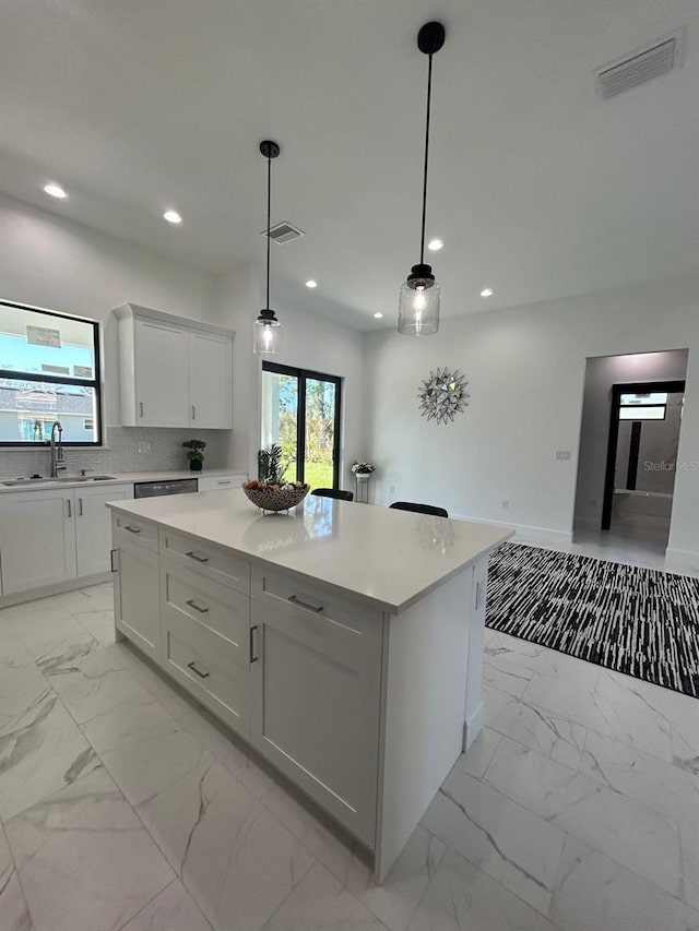 kitchen with a center island, white cabinetry, hanging light fixtures, and sink