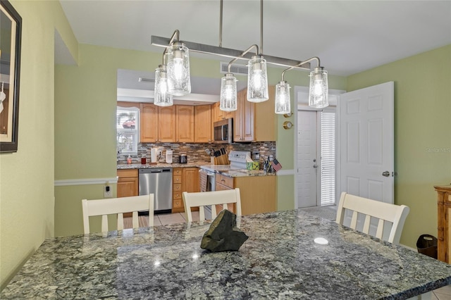 kitchen featuring decorative light fixtures, stainless steel appliances, stone counters, and decorative backsplash